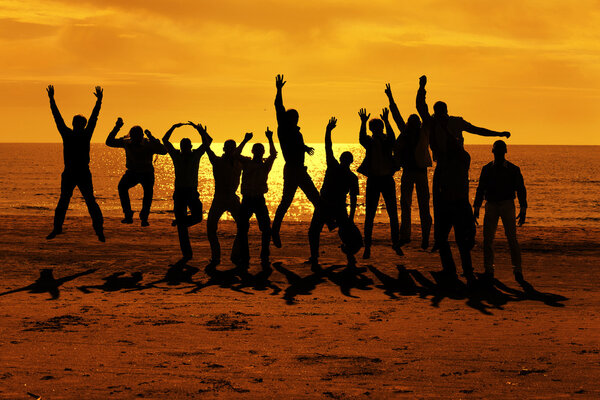 Male friends are having fun and jumping up on the sunset