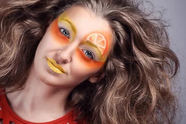 Closeup portrait of young female with orange fantasy makeup on grey background Stock Image