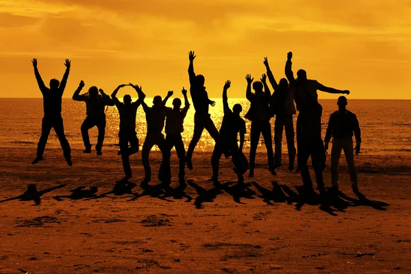 Mannelijke vrienden zijn met plezier en springen op de zonsondergang Stockfoto