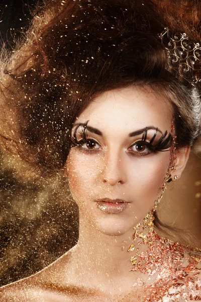 Portrait of beautiful female on carnival in golden shimmery glitter and sparkles looking to the camera — Stock Photo, Image