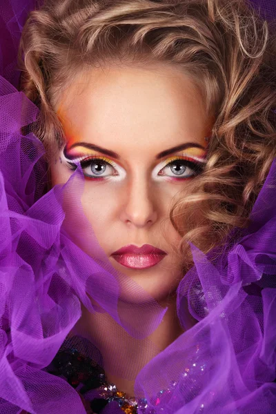 Retrato de mujer joven atractiva caucásica en encaje púrpura y red con maquillaje de estilo fantasía y rizos rubios mirando directamente a la cámara Imágenes de stock libres de derechos