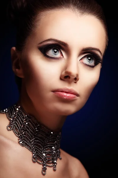 Mulher bonita gótica com olhos azuis bonitos gigantes e maquiagem à noite no fundo preto olhando para o lado direito — Fotografia de Stock