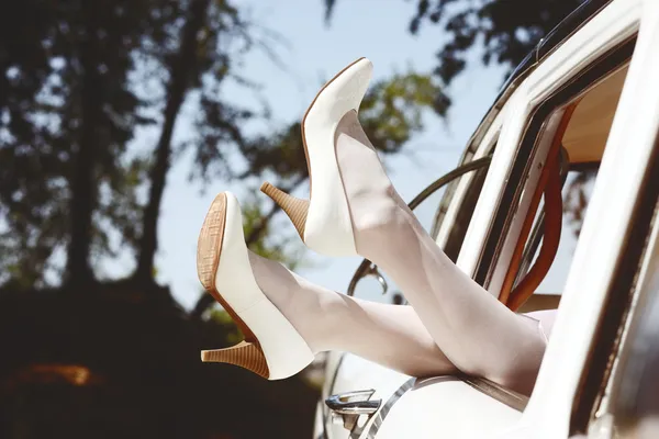 白色皮革高跟鞋复古婚礼车窗外的苗条漂亮新娘腿 — 图库照片
