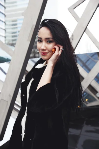 Smiling asian business woman in London standing on the street in the city and talking by the mobile phone — Stock Photo, Image