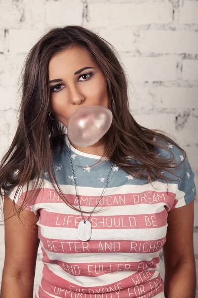 Jovem americana fêmea está mastigando sua pastilha elástica e soprando bolhas fora dele — Fotografia de Stock