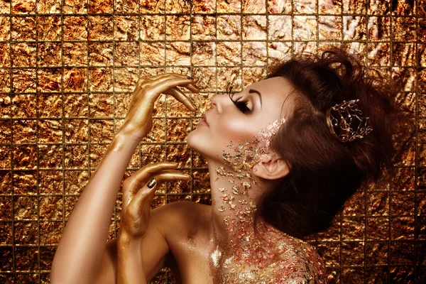 Attractive addicted hot brunette with beautiful golden makeup and gold caramel painted hands is posing in front of abstract golden background — Stock Image Attractive addicted hot brunette with beautiful golden makeup and gold caramel painted hands is posing in front of abstract golden background Royalty Free Stock Photos