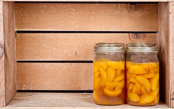Canned peaches in a rustic crate — Stock Photo, Image