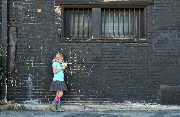 Menina de pé ao lado da parede de tijolo — Fotografia de Stock