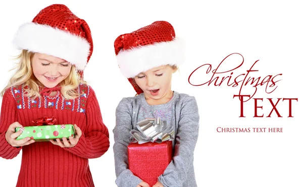 Dos niños sosteniendo regalos con sombreros de Santa Claus —  Fotos de Stock