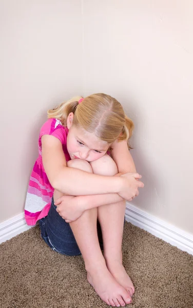 Sad child sitting in corner — Stock Photo, Image