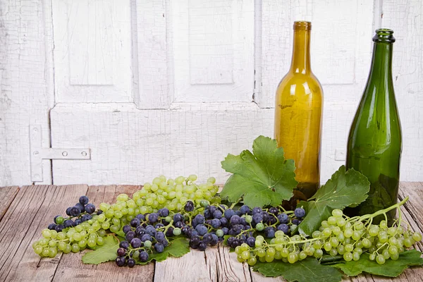 Виноград і пляшки на дерев'яній дошці — стокове фото