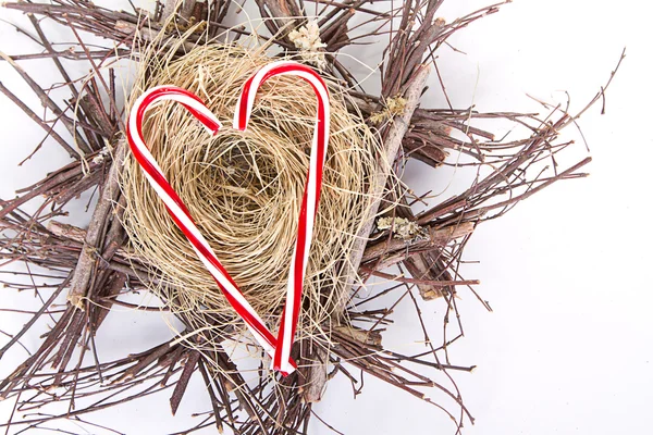 Candy canes in the shape of a heart on a nest — Stock Photo, Image