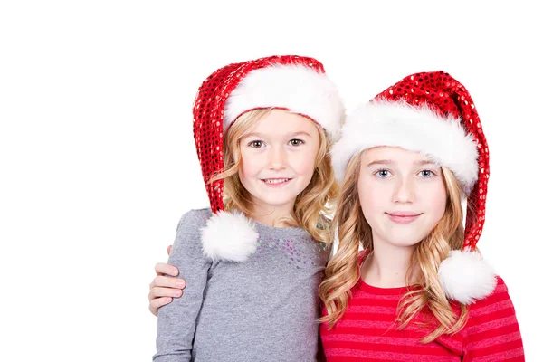 Zusters of twee jonge meisjes dragen santa hoeden — Stockfoto