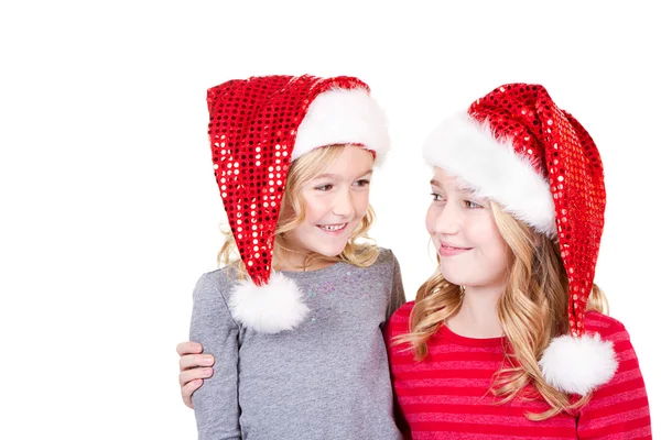 Sisters or two young girls wearing Santa hats — Stock Photo, Image