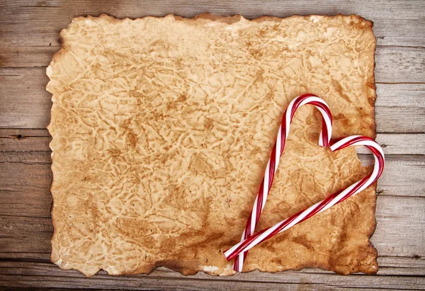 Torn paper onwooden background with candy canes — Stock Photo, Image