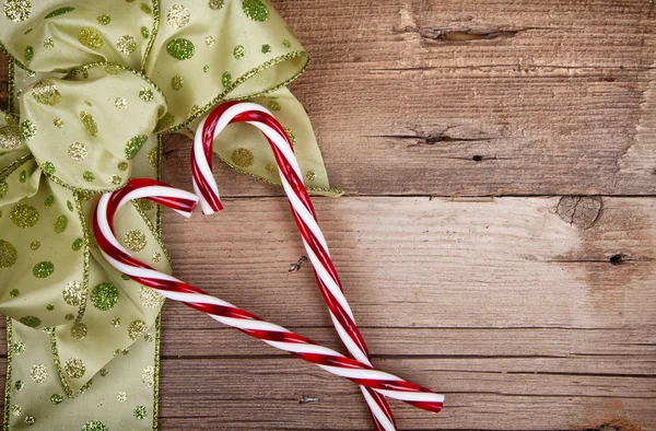 Christmas ribbon and candy canes on wooden background — Stock Photo, Image