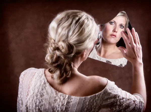 Donna che guarda in uno specchio rotto — Foto Stock