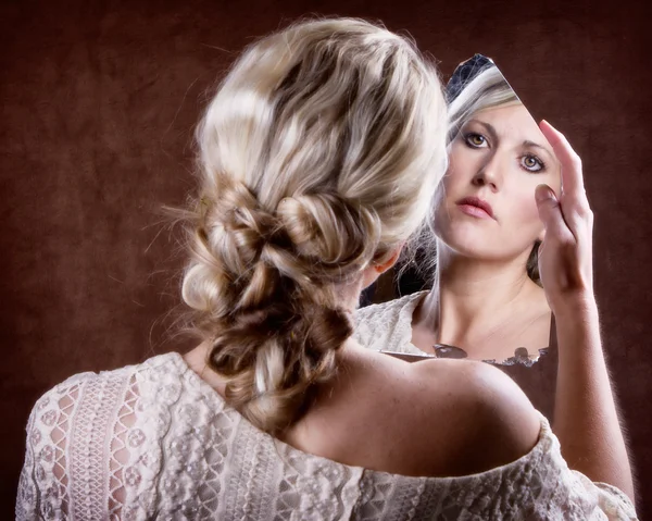 Woman looking into a broken mirror — Stock Photo, Image