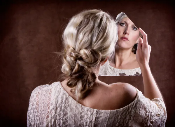 Woman looking into a broken mirror — Stock Photo, Image