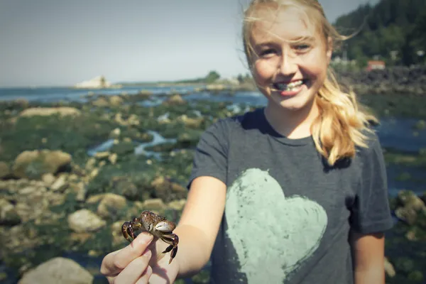 Girl  holding a crab standing near tidal pools at Tillamook bay — Stock Photo, Image