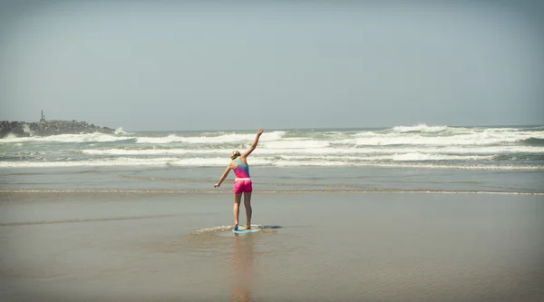Girl or teen learning to ride a skimboard on the Oregon coast — Stock Photo, Image