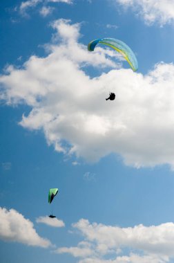 İki paraşütler bulutlar arka planı mavi gökyüzünde uçan. Güneşli bir havada yamaç paraşütü.