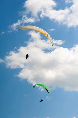 İki paraşütler bulutlar arka planı mavi gökyüzünde uçan. Güneşli bir havada yamaç paraşütü.
