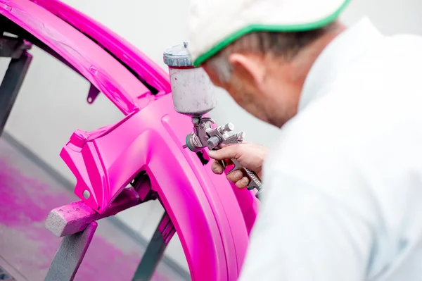 Человек рисует фиолетовый бампер машины в специальной будке — стоковое фото