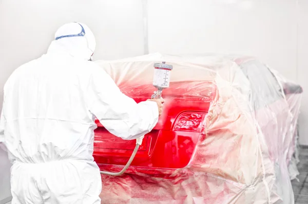 Auto mechanic painting with airbrush a red car in special booth — Stock Photo, Image