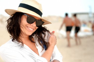 gülümseyen Resort'un özel plajında şapka ve gözlük takan kadın