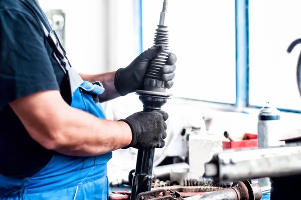 Automechaniker arbeitet an Stoßdämpfer und Autoteilen — Stockfoto