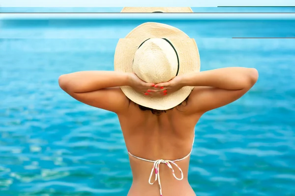 Счастливая женщина наслаждается солнцем на пляже в шляпе летом — стоковое фото
