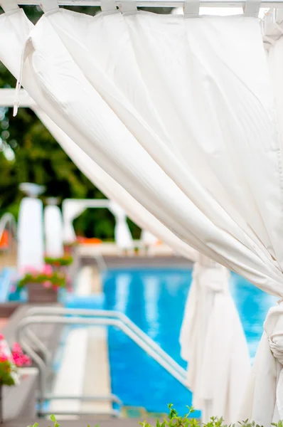 Close-up detail of white sunbeds inside tend by a modern pool — Stock Photo, Image