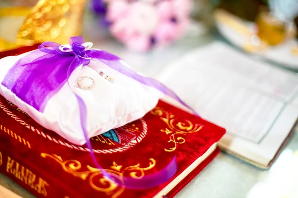 Anillos de boda en un cojín con la Biblia santa debajo — Foto de Stock