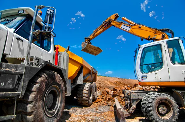 Stor, industriella grävmaskin på nya byggarbetsplats laddar dumper lastbilar — Stockfoto