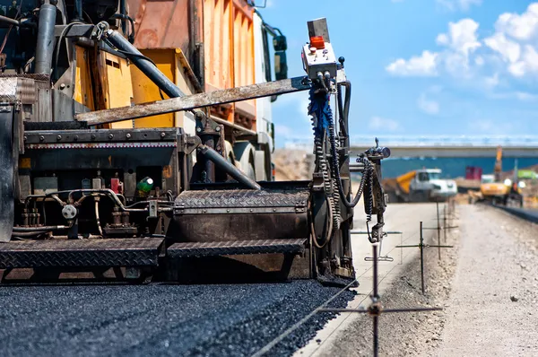Pavement machine laying fresh asphalt or bitumen on top of the gravel base — Stock Photo, Image
