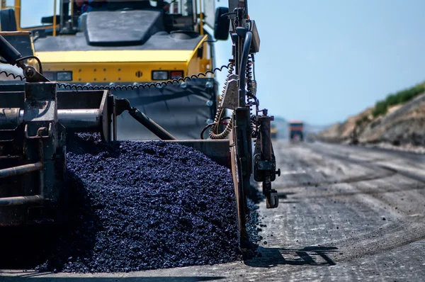 Máquina de pavimento industrial que coloca asfalto fresco na nova estrada — Fotografia de Stock