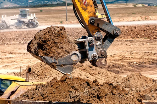 Close-up van zware graafmachine scooping in aarde en laden — Stockfoto