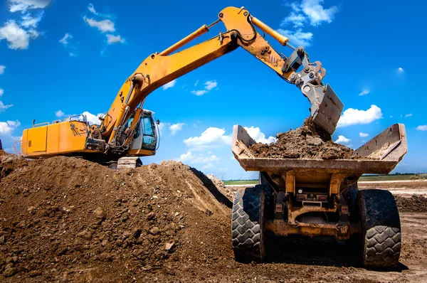 Excavatrice chargeant benne bascule camion benne dans le bac à sable — Photo