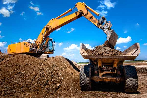 Excavator loading dumper truck tipper in sandpit