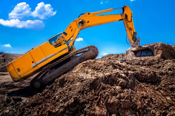 Industrial excavator climbing on soil material — Stock Photo, Image