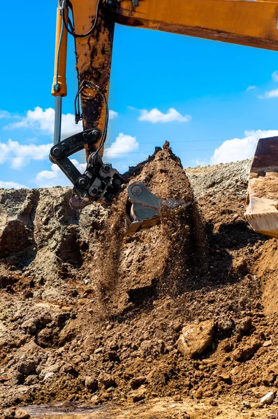 Heavy duty excavator scooping sand and loading dumper trucks — Stock Photo, Image
