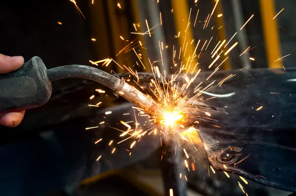 Промышленный рабочий сварочный металл на сталелитейном заводе с искрами — стоковое фото