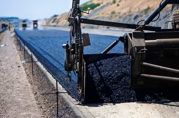 Camión de pavimento industrial que pone asfalto fresco en el sitio de construcción Imagen De Stock