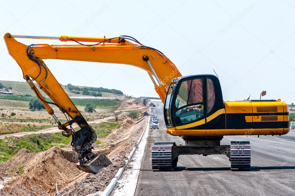 Heavy duty excavator working in sand on the side of road construction site