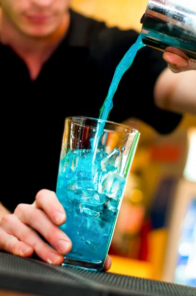 Cantinero vierte bebida alcohólica en vaso de cóctel haciendo un curacao azul — Foto de Stock