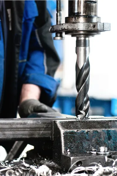 Nahaufnahme eines Industriearbeiters, der ein Loch in eine Metallstange bohrt — Stockfoto