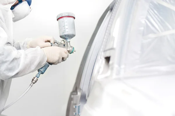 Trabajador pintando un coche blanco en un garaje especial —  Fotos de Stock