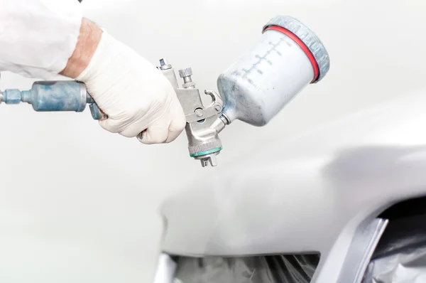Close-up van een spray paint pistool, schilderij van een auto. werknemer schilderij de motorkap van een auto — Stockfoto