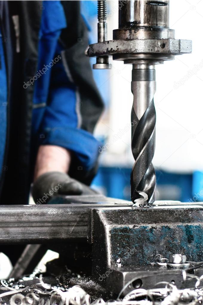 Close-up of industrial worker drilling a hole in a metal bar